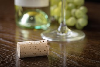 Blank wine cork resting on wood table near grapes
