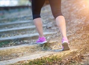 Young fit adult woman outdoors walking or running up wooden steps