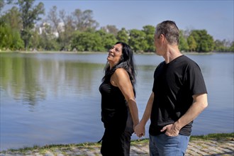 Multi-ethnic couple formed by an Andean woman and a Caucasian man walking by a lake. Happy expressions and faces of lovers