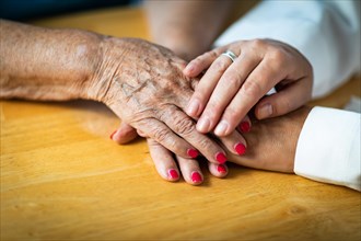 Younger female hands holding senior adult woman hands