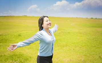 Young woman smiling and spreading her hands in the green field