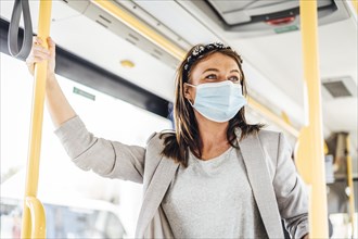 A young woman wearing protective mask commuting by the public bus