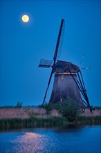 Netherlands rural landscape with windmills at famous tourist site Kinderdijk in Holland in twilight with full moon
