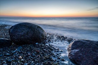 Langzeitbelichtung von grossen Felsbrocken am steinigen Strand der Ostsee bei Sonnenuntergang