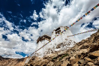 Ruins of Victory Fort Tsemo on the cliff of Namgyal hill and colorful Buddhist prayer flags with Buddhism mantra written on them. Leh