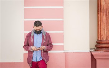 Guy with face mask checking his cell phone