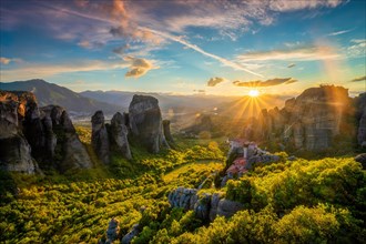 Sunset over monastery of Rousanou and Monastery of St. Nicholas Anapavsa in famous greek tourist destination Meteora in Greece on sunset with sun rays and lens flare