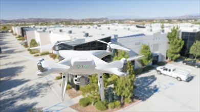 Unmanned aircraft system quadcopter drone in the air near corporate industrial building