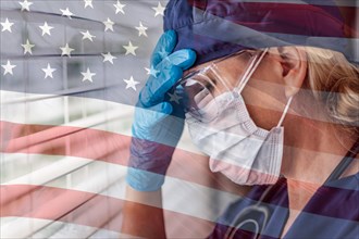 Stressed female doctor or nurse on break at window wearing medical face mask and goggles with ghosted american flag
