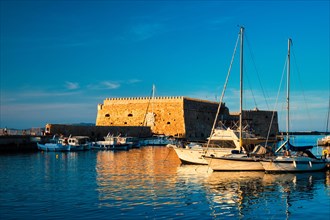Venetian Fort Venetian fortress of Koules Castello in Heraklion and moored Greek fishing boats in port