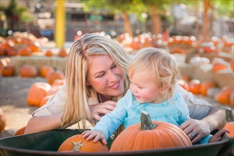 Adorable young mother and daughter enjoys a day at the pumpkin patch