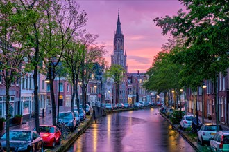 Canal with parked along cars in Delft town in evening dusk after rain
