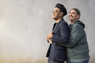 Gay latin couple wearing fashionable hats hugging in the street. Copy space