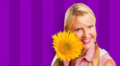 Beautiful girl holding yellow sunflower against purple striped background
