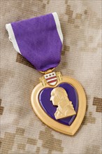 Purple heart medal laying on military fatigues