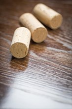 Blank wine corks resting on reflective wood surface
