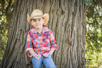 mixed-race young boy wearing cowboy hat standing outdoors