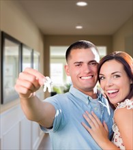 Happy military couple with house keys inside hallway of new home