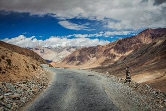 Road in Himalayas near Kardung La pass with stone cairn
