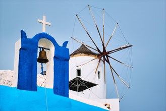 Old traditional whitewashed greek windmill and orthodox christian church bell on Santorini island in Oia town