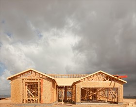 Wood home framing abstract at construction site with stormy clouds behind