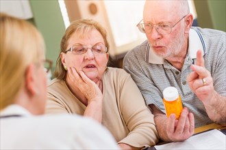 Doctor or nurse explaining prescription medicine to senior adult couple