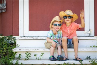 mixed-race chinese and caucasian young brothers having fun wearing sunglasses and cowboy hats