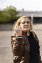 Young blonde woman showing lgbt wristband