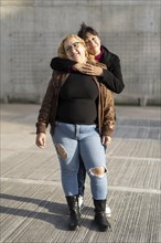 Couple of lesbian women hugging in a park looking at the camera smiling. Copy space