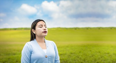 A young woman breathing deeply in the field