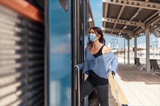 A young woman in protective mask getting on the train with a luggage