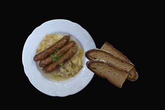 Bratwurst with cabbage and bread on a black background