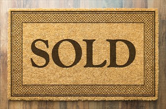Sold welcome mat on A wood floor background