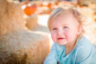 Adorable baby girl having fun in a rustic ranch setting at the pumpkin patch