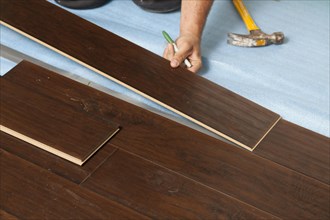 Man installing new laminate wood flooring abstract