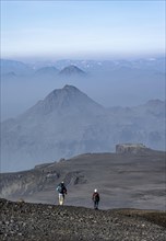 Two hikers on trail through volcanic landscape
