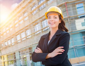 Portrait of young attractive professional female contractor wearing hard hat at construction site