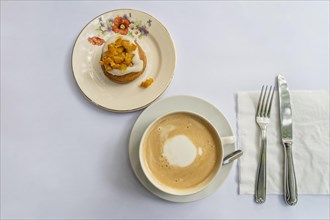 Top view of a latte and an orange cupcake on vintage crockery