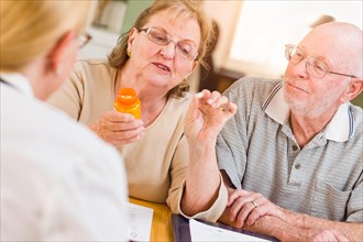 Doctor or nurse explaining prescription medicine to senior adult couple