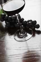 Abstract wine glass and grapes on a reflective wood surface