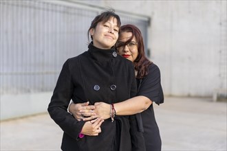 Couple of lesbian women hugging in a park looking at the camera. Copy space