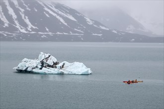 Canoeist in front of iceberg in St. Jonsfjorden