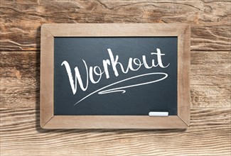 Workout written on slate chalk board against aged wood background