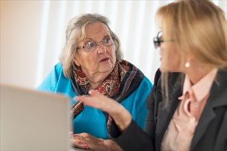 Woman helping senior adult lady on laptop computer