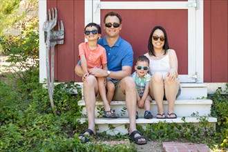 Portrait of caucasian and chinese couple with their mixed-race young boys wearing sunglasses