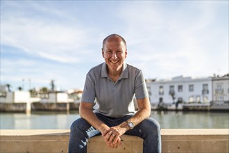 Portrait of smiling man relaxing by the riverbank in touristic and historic Tavira