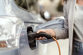 A young woman charging an electric car in urban settings