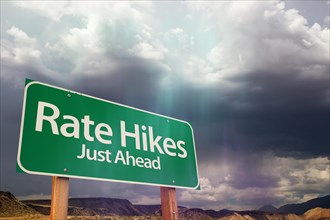 Rate hikes green road sign over dramatic clouds and sky