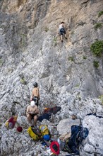 Young man belays a climber on lead