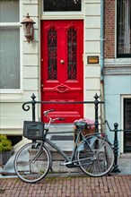 Bicycle near door of old house in Amsterdam street. Bicycles are the very popular means of transport in Netherlands. Amsterdam